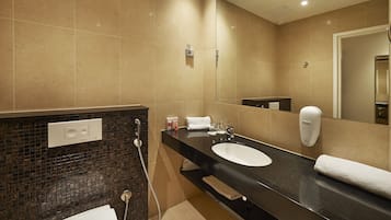 Een moderne badkamer met een zwart aanrecht, een witte wastafel en een grote spiegel.