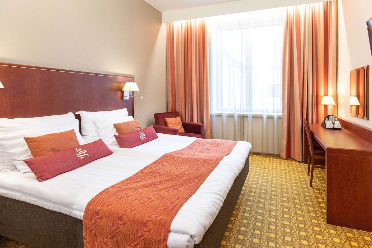 Hotellihuone, jossa on suuri sänky, työpöytä ja tuoli.