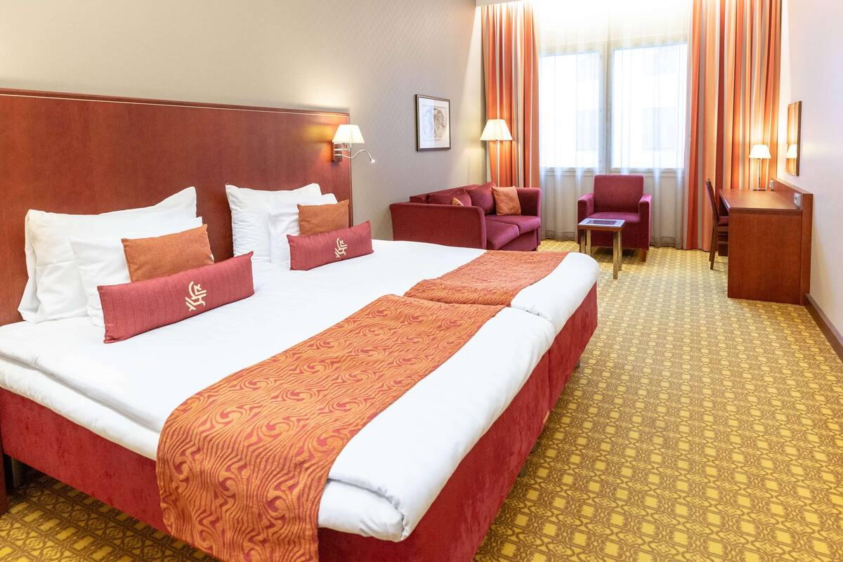 Hotellihuone, jossa on suuri sänky, sohva, työpöytä ja tuoli.