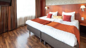 A hotel room with a large bed, wooden flooring, a TV mounted on the wall, and a window with curtains. - Scandic Atlas (Kuopio)