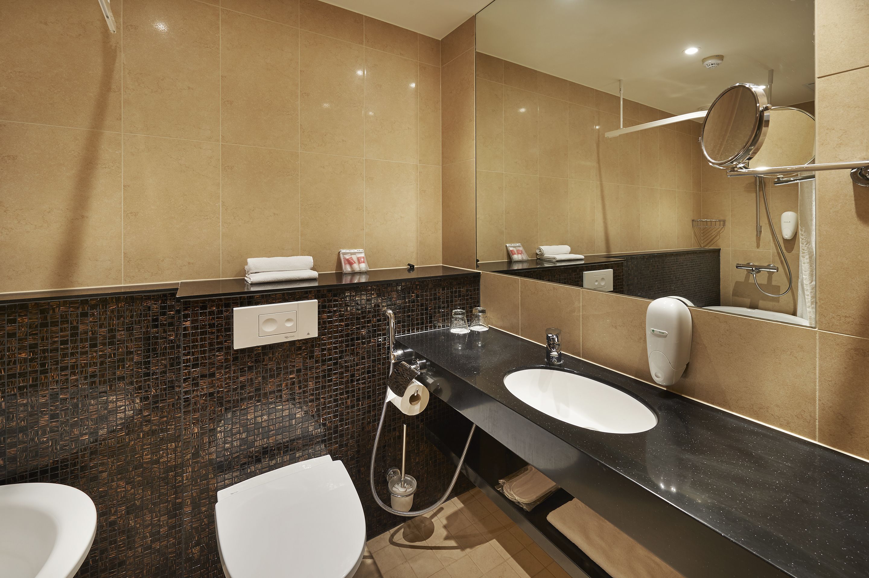 A modern bathroom with two sinks, a large mirror, and a shower area.
