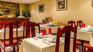 A dining area with tables set for breakfast, featuring a variety of food items and beverages.