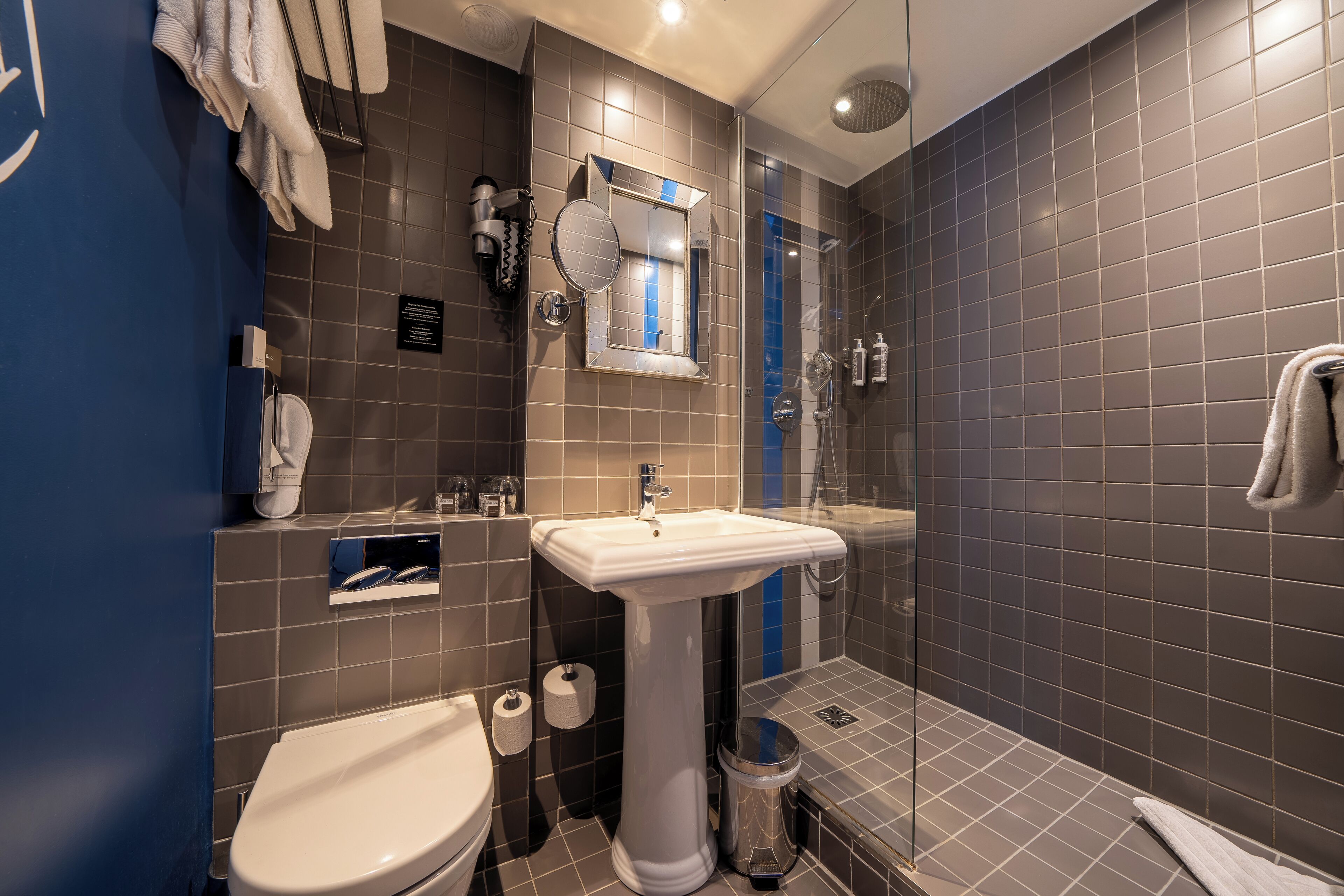 Un baño moderno con lavamanos pedestal, inodoro y ducha.