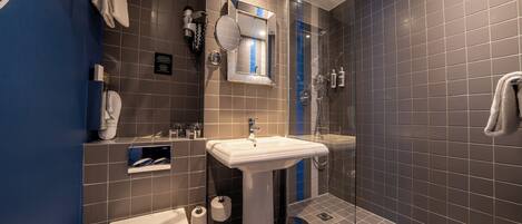 Un baño moderno con lavamanos pedestal, inodoro y ducha.