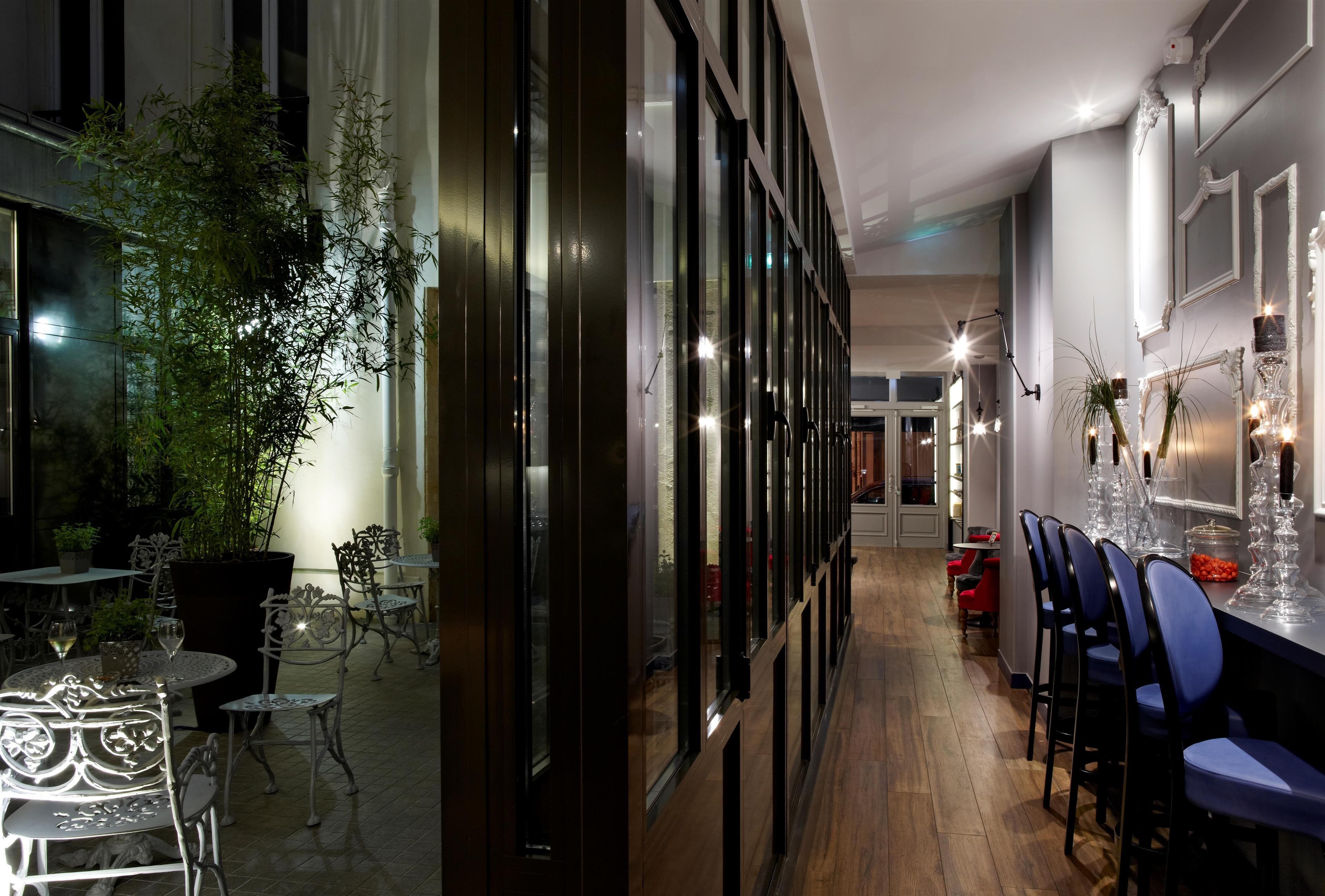 An indoor dining area with tables and chairs, a large potted plant, and a bar area with stools.