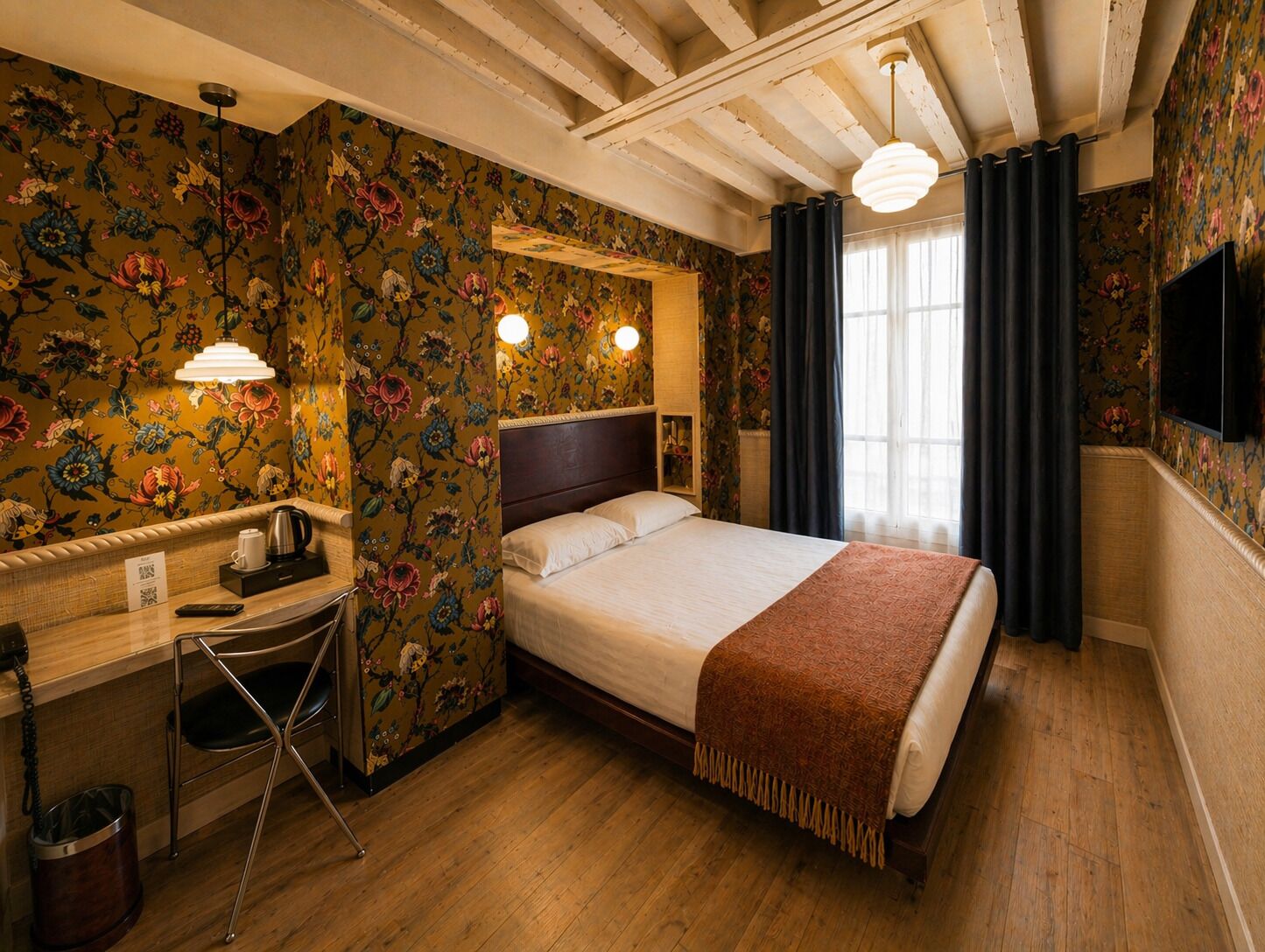 A hotel room with a bed, desk, chair, and a television.