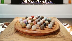 Un interior moderno con chimenea, una pieza decorativa en la pared y una mesa de madera con piedras de colores.
