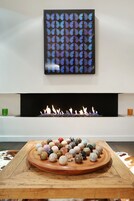 Un interior moderno con chimenea, una pieza decorativa en la pared y una mesa de madera con piedras de colores.