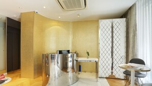 A reception area with a marble reception desk, a small table with a magazine, and a seating area with a chair. - Nouvel Hotel Eiffel (Paris)