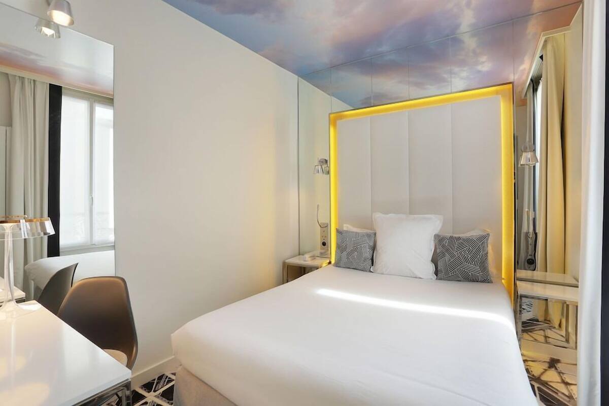 Ein modernes Hotelzimmer mit einem großen Bett, einem Nachttisch, einem Sessel und einem Schreibtisch.