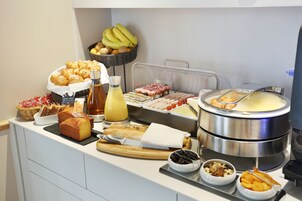 Un bufé con diversos alimentos, incluyendo pasteles, frutas y una olla caliente.