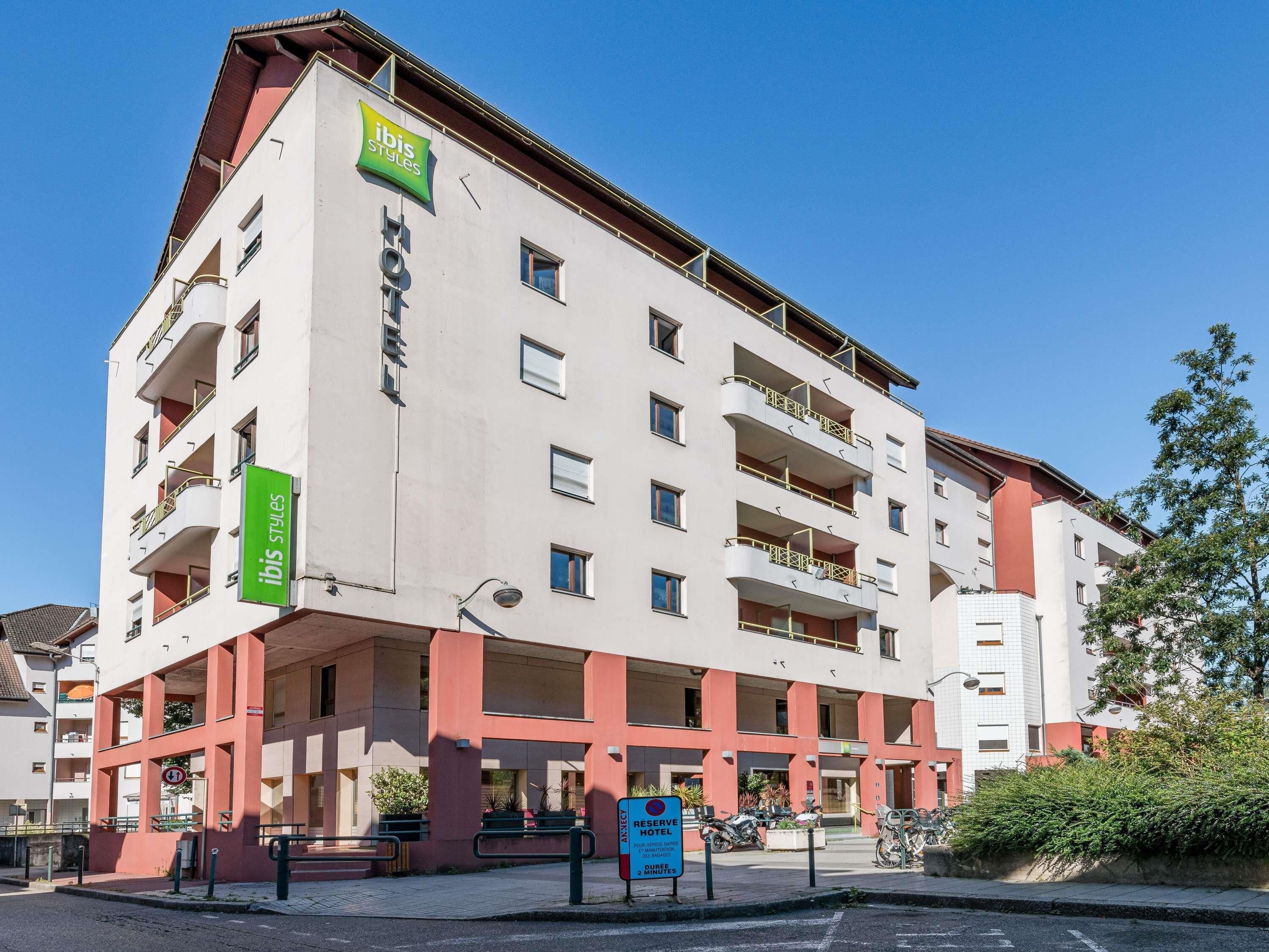 A multi-story hotel with a modern design, featuring balconies on each floor, a visible entrance, and a sign indicating it is part of the ibis Styles hotel chain.