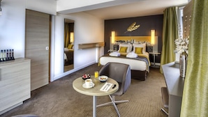 Habitación de hotel con cama, escritorio, silla, una pequeña mesa con desayuno y baño.