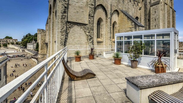 Un edificio histórico de piedra con ventanas de arco y un balcón adornado con macetas.