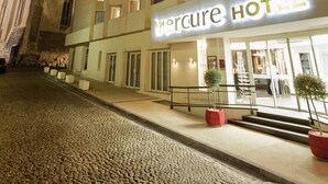 Un hotel con fachada moderna, varios pisos y una entrada destacada con un cartel.