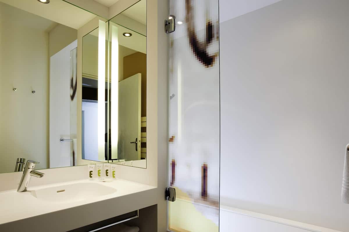 Ein modernes Badezimmer mit Duschkabine aus Glas, einem weißen Waschbecken und einem großen Spiegel.
