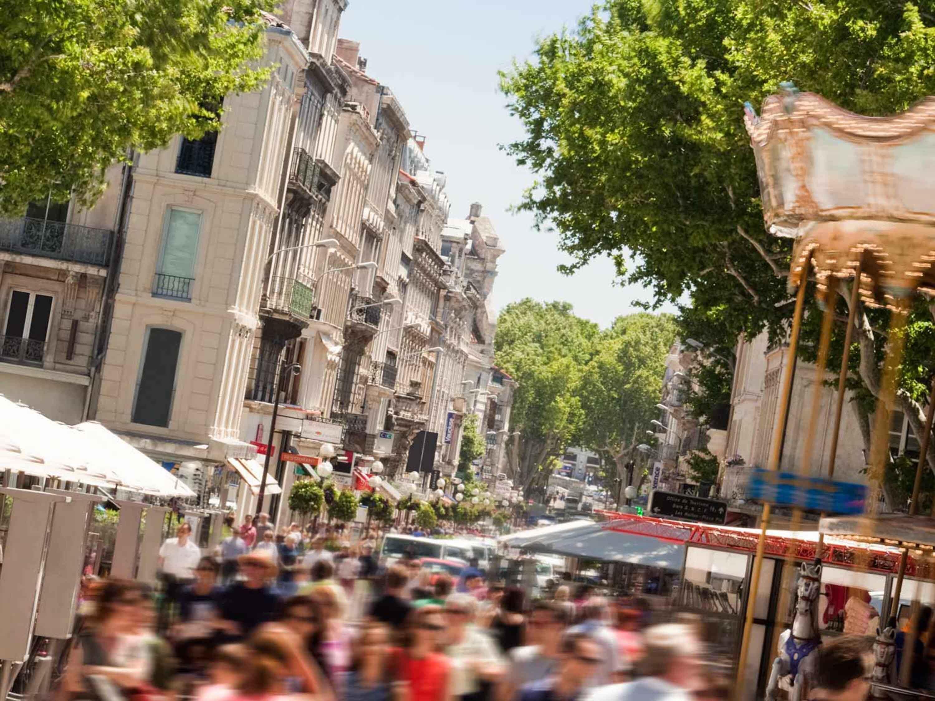 Una calle concurrida, edificios históricos, un carrusel y una multitud de gente.