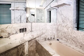 Un baño moderno con paredes de mármol, lavamanos doble y bañera.