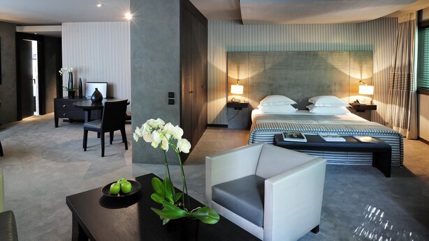 Quarto de hotel moderno com uma cama grande, uma escrivaninha, uma cadeira e um sofá.