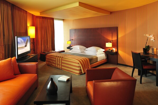 A hotel room with a bed, a TV, a desk, a chair, and a sofa.