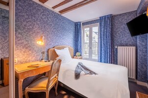 Una camera d'albergo con un letto, una scrivania, una sedia, una lampada e una TV.