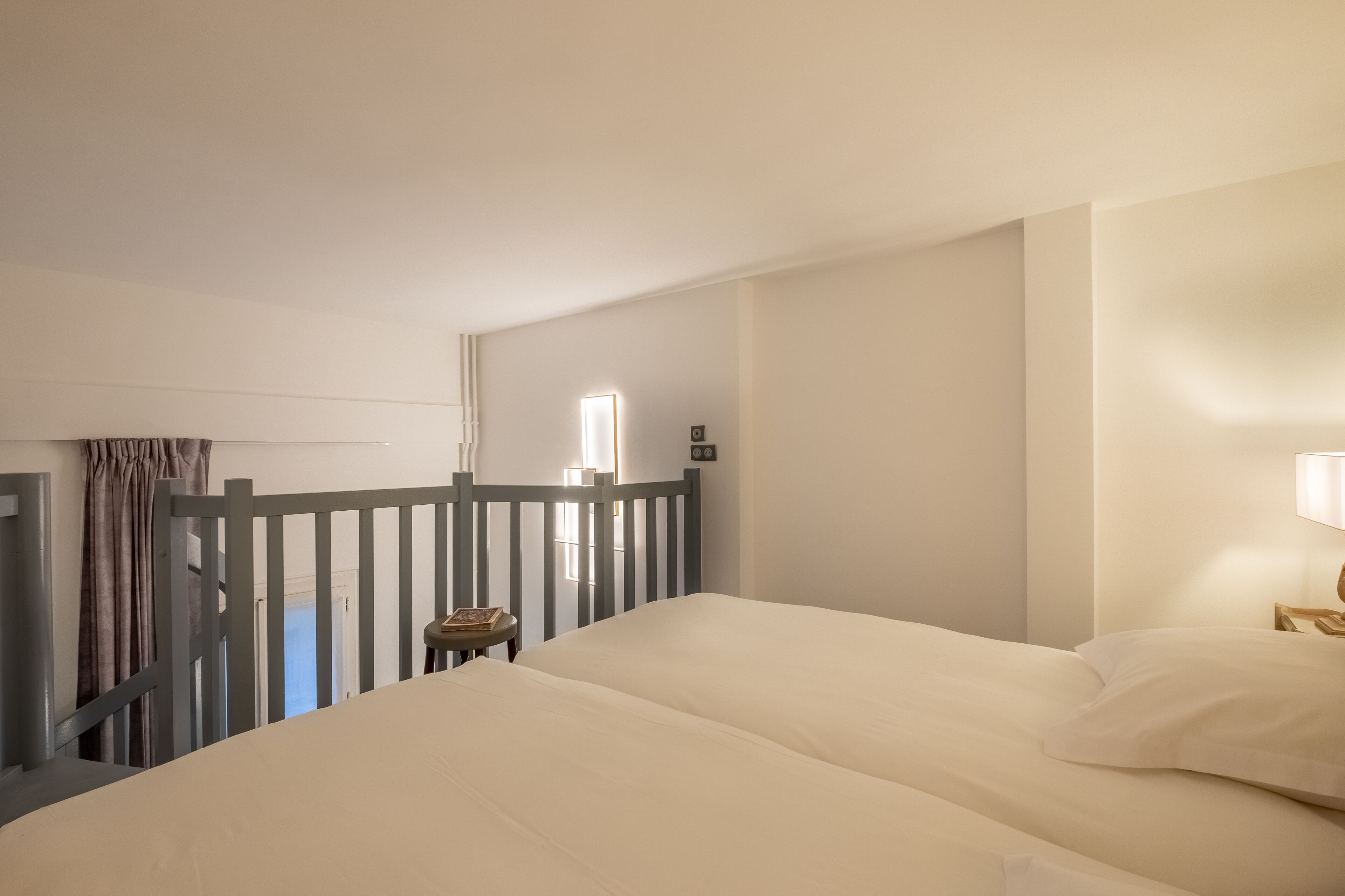 Una camera d'albergo con un letto, un comodino, una lampada e vista all'esterno.