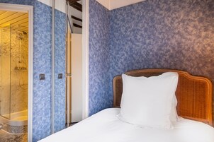 Una camera d'albergo con un letto, una cabina doccia e una parete blu con texture.