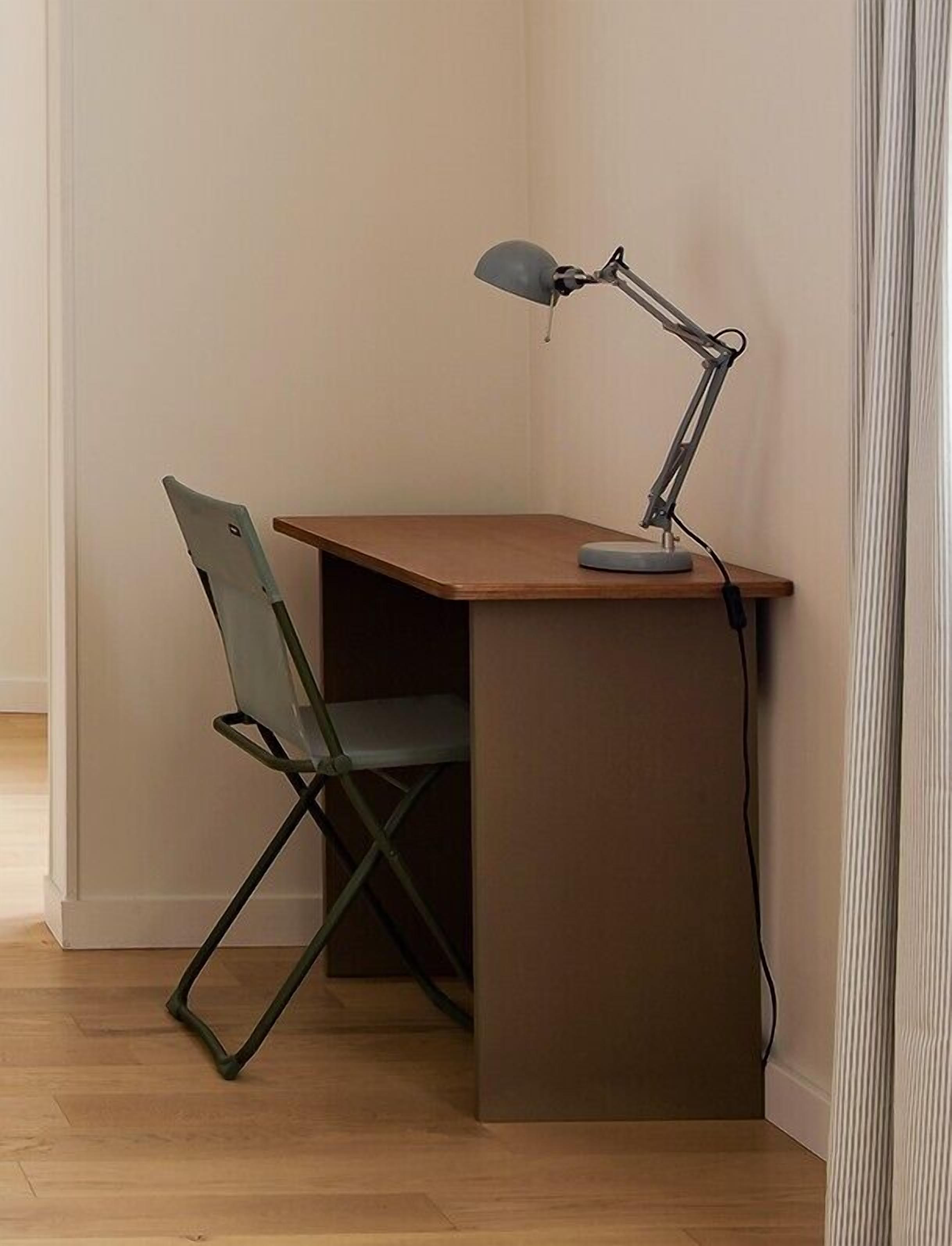 A corner desk with a chair and a desk lamp.