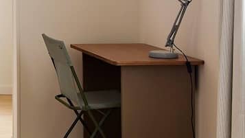 A corner desk with a chair and a desk lamp.