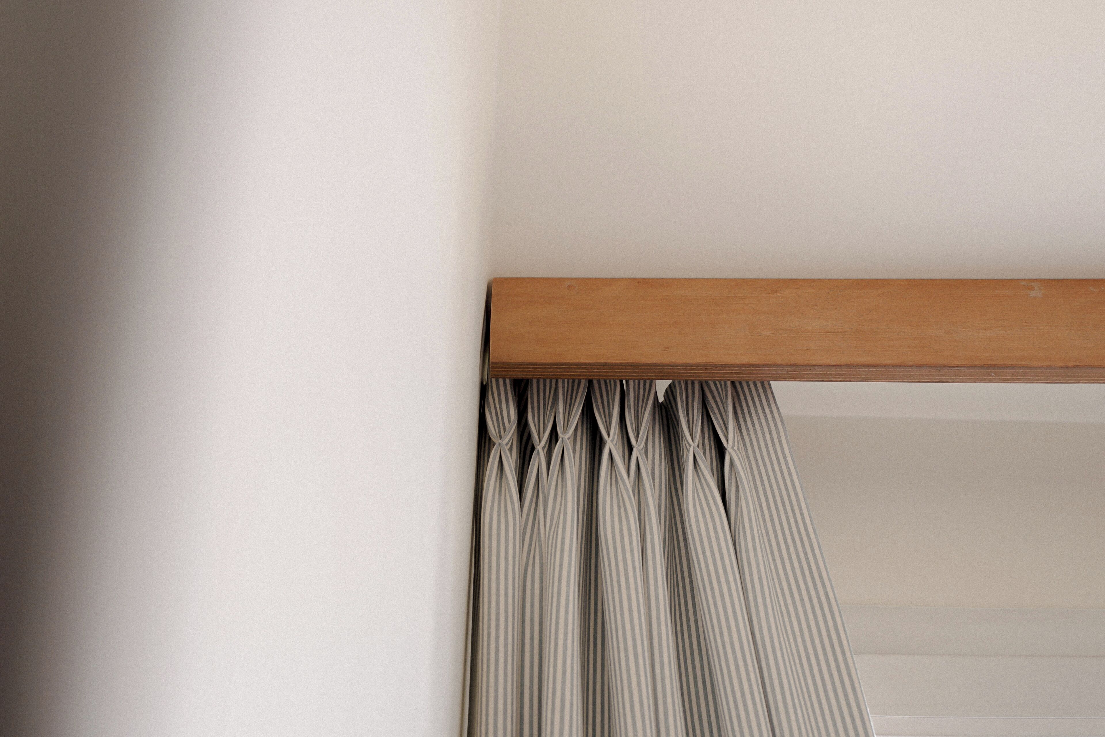 A corner of a room with a wooden beam and a striped curtain.