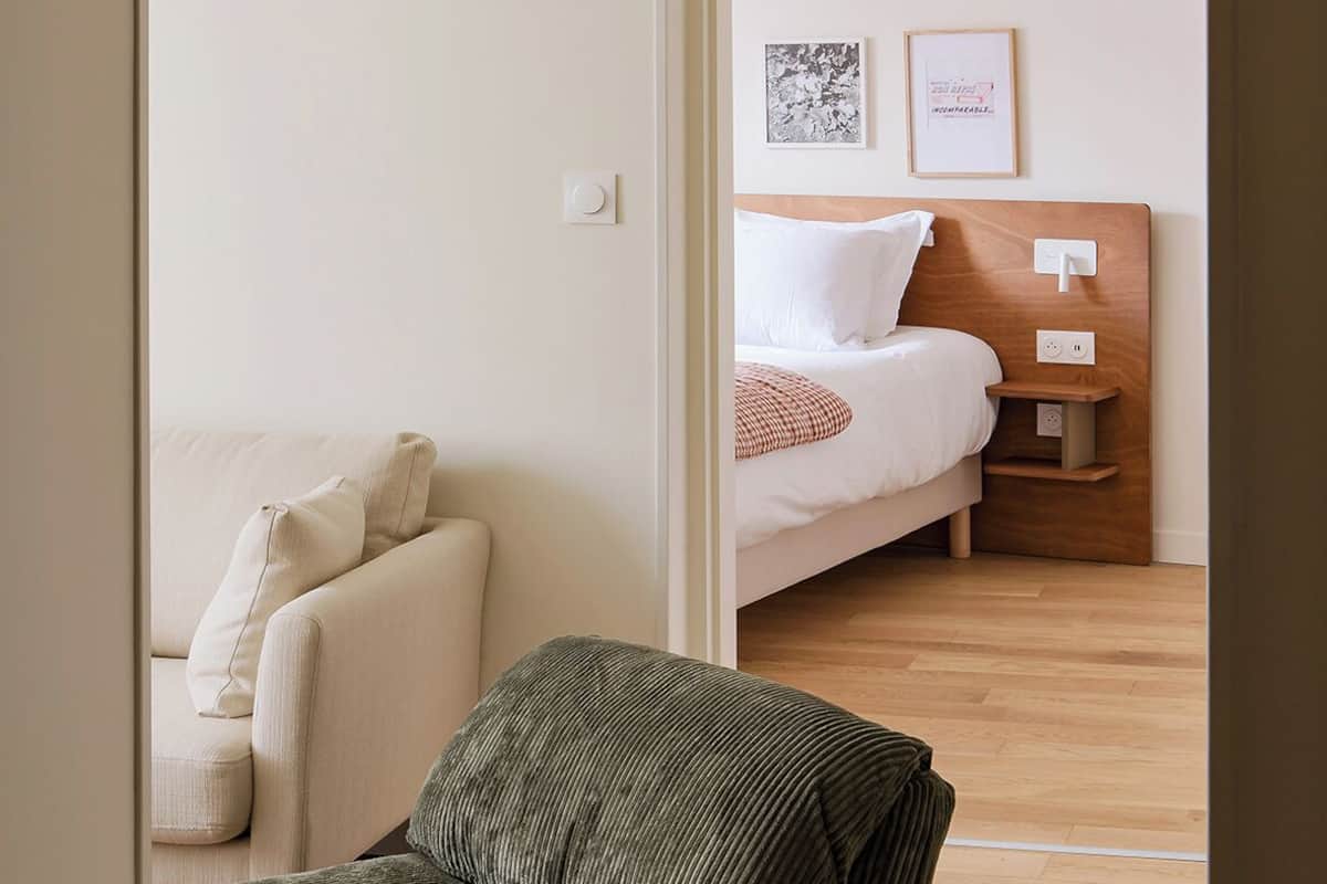 Una habitación con una cama, un sofá y una mesita de noche con una lámpara.