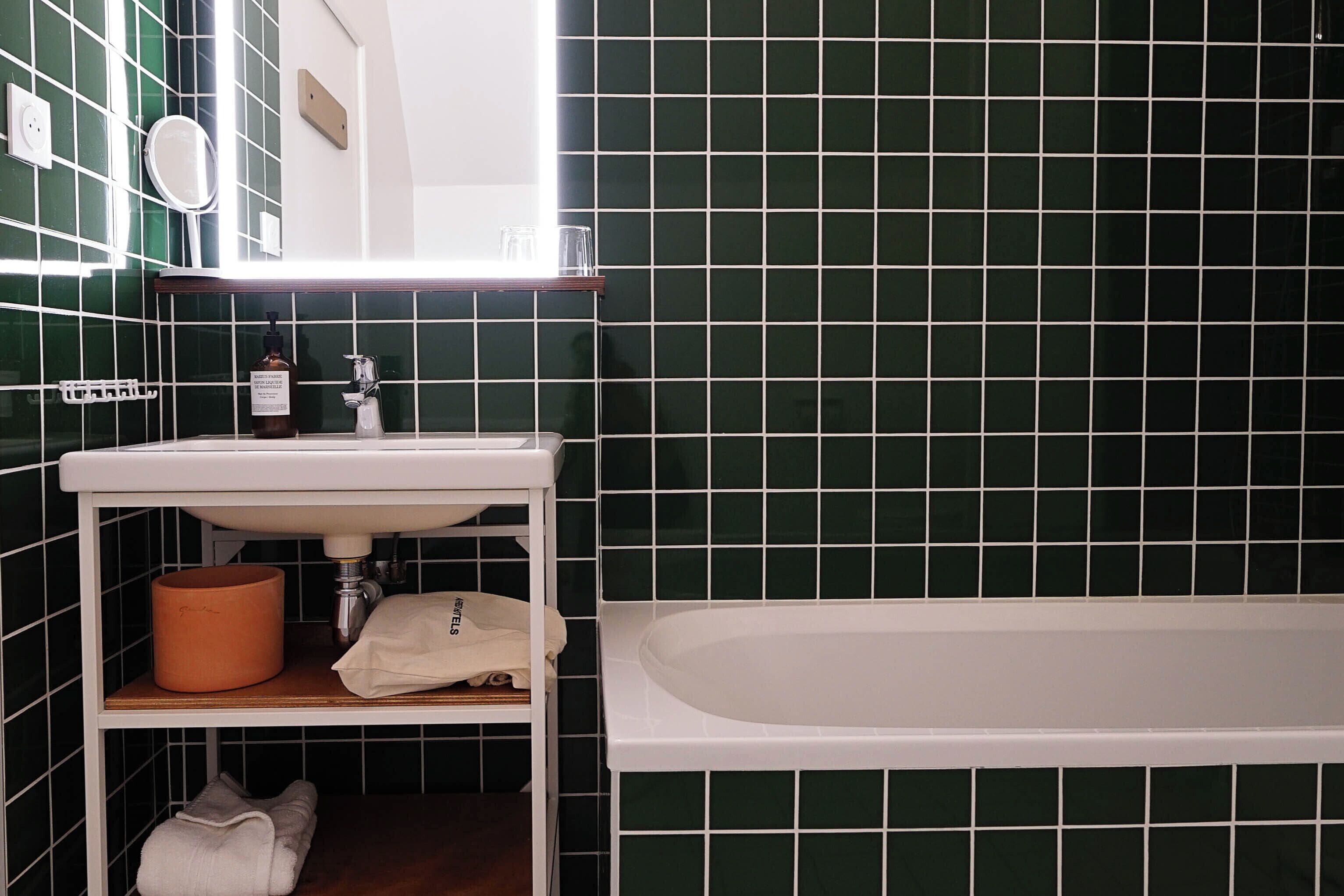 Un baño con lavamanos blanco, espejo y bañera.