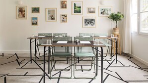 Een vergaderruimte met een lange tafel, groene stoelen en ingelijste foto's aan de muur.