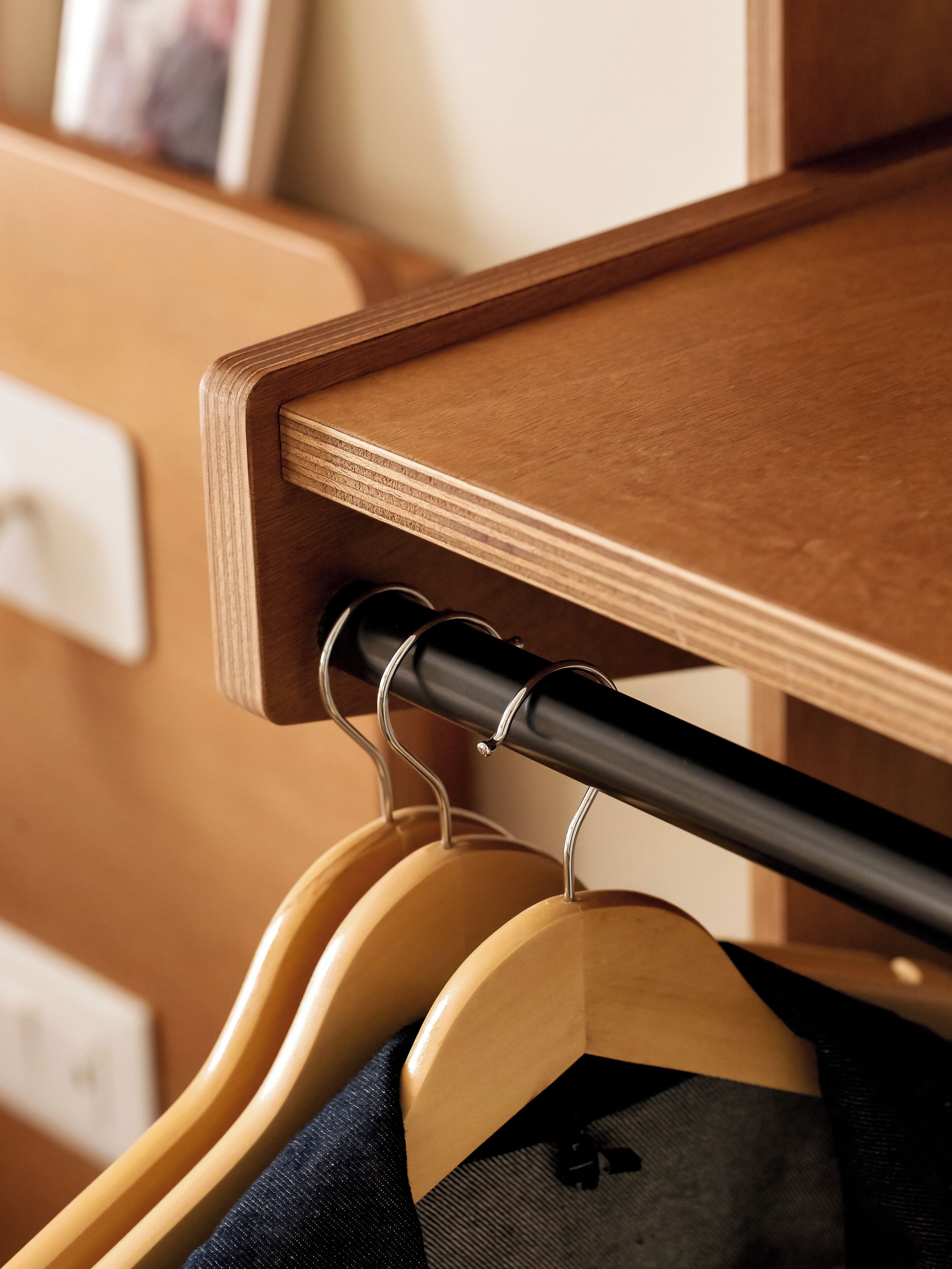 A wooden coat rack with hangers holding clothes.