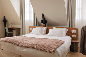 Una habitación de hotel con una cama, un escritorio y una silla.