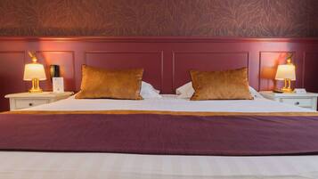 A neatly made bed with two pillows, a purple headboard, and bedside lamps.