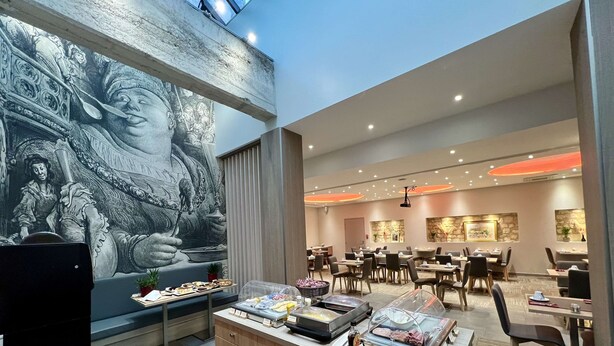 A modern dining area with a mural, buffet, and seating arrangements.
