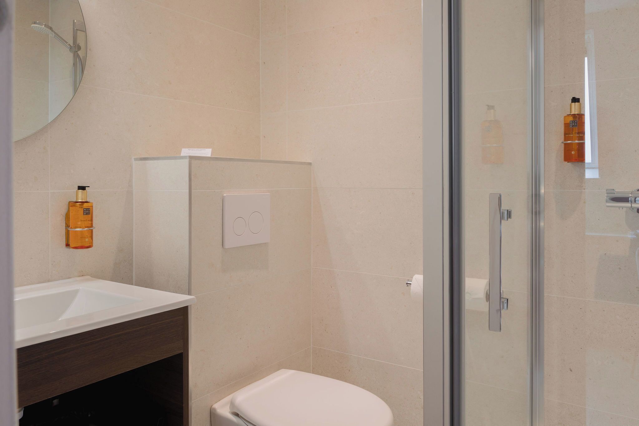 A modern bathroom with a glass shower enclosure, a white sink, and a toilet.
