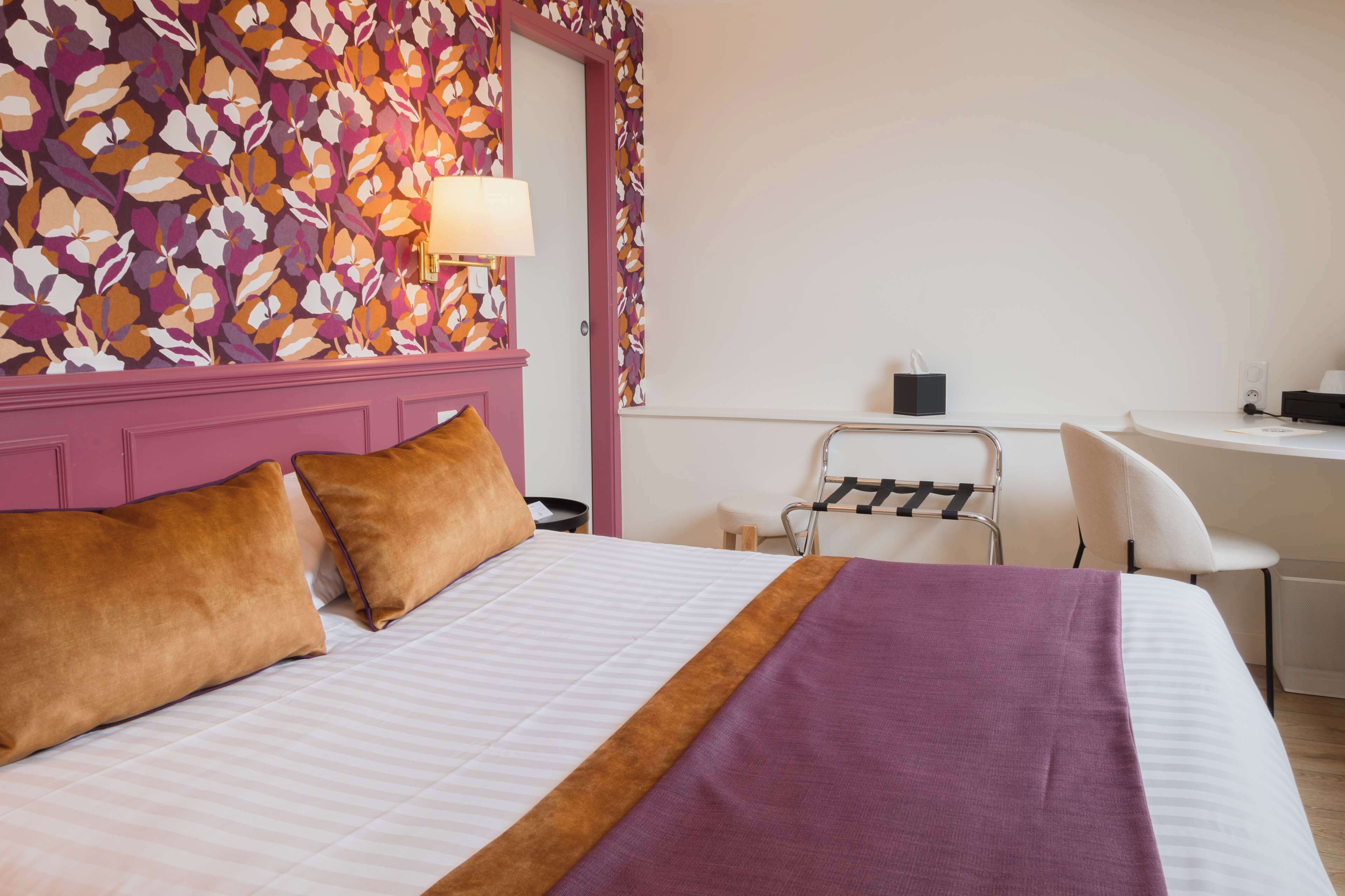 A hotel room with a bed, a desk, and a chair.