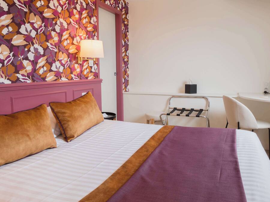 A hotel room with a bed, a desk, and a chair.