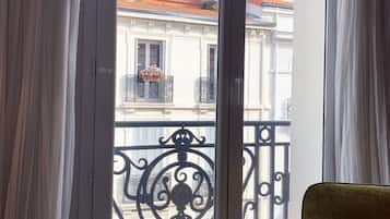 Ein Zimmer mit einer großen Schiebeglastür, die auf einen Balkon mit schmiedeeisernem Geländer führt.