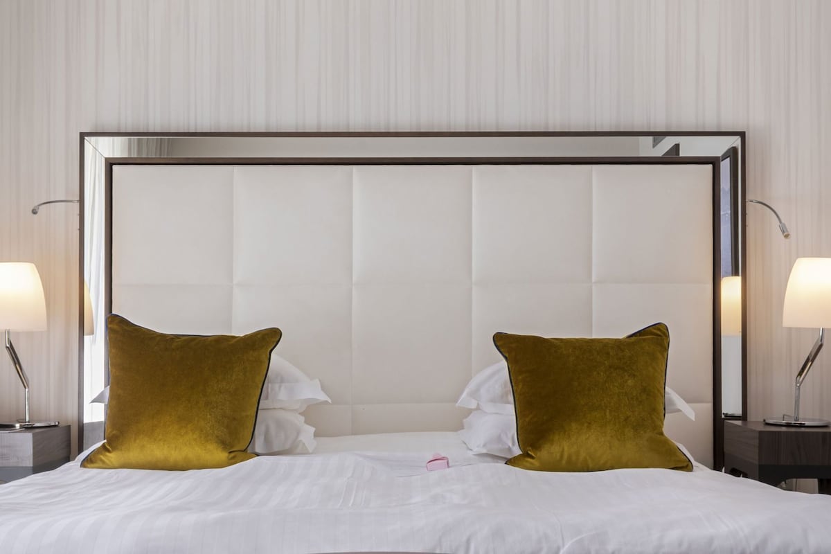 Ein Hotelzimmer mit einem großen Bett, zwei Nachttischlampen und einem Kopfteil.
