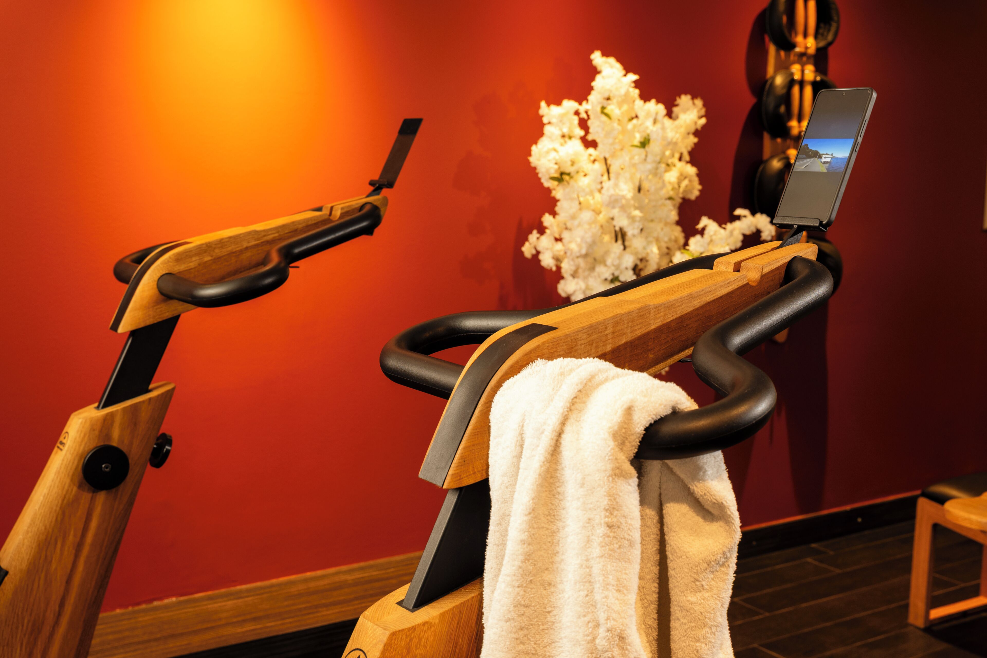 An exercise machine with a towel, a wooden structure, and a wall with a red hue.