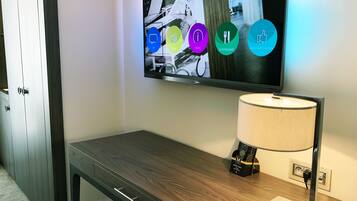 A modern hotel room with a flat-screen TV mounted on the wall displaying a digital interface.
