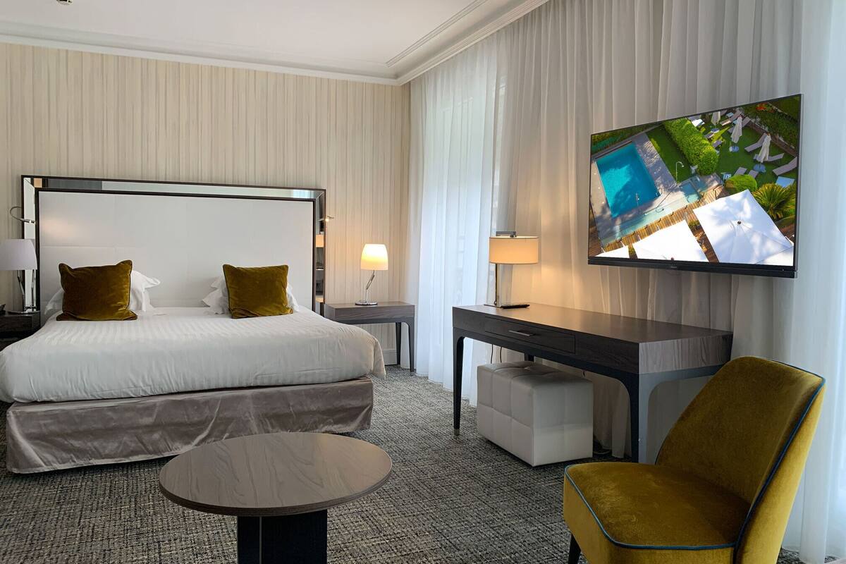 Une chambre d’hôtel avec un grand lit, un bureau, une chaise, une télévision et une vue sur la piscine.