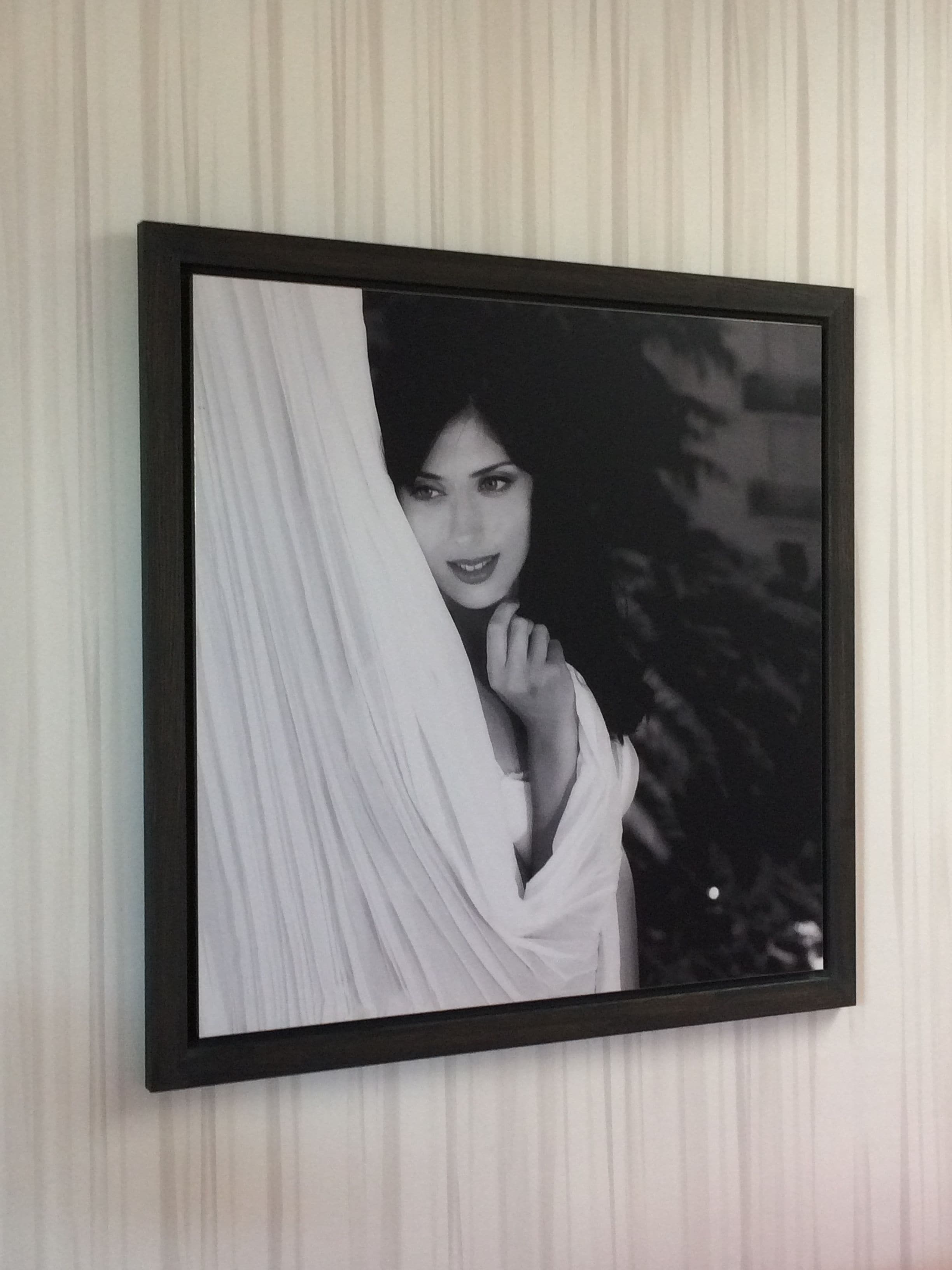 A framed photograph of a person in a white garment with a black frame on a wall.