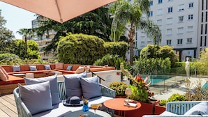 Eine Dachterrasse mit Sitzbereichen, einem Pool und üppiger Bepflanzung.