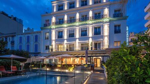 Ein mehrstöckiges Hotel mit Schwimmbad, Außenbereich und gut beleuchteter Fassade.