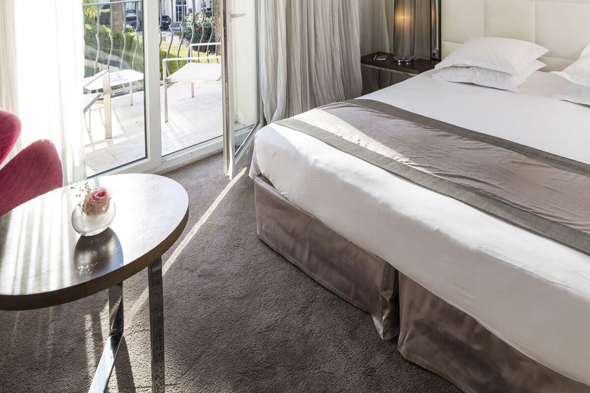 Une chambre d’hôtel avec un lit, une table ronde, une chaise, une table de chevet et une vue sur l’extérieur.