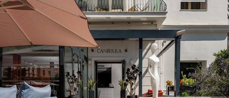 Un bâtiment moderne doté d’un espace café avec des places assises en plein air et des plantes en pot.